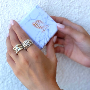 Hand wearing multiple silver rings and bracelets on a white background