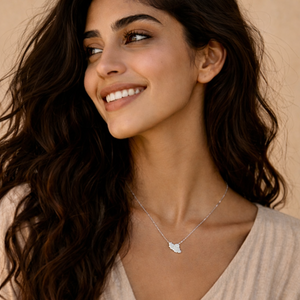Woman wearing a silver Iran Map necklace with a beige top against a neutral background