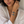 Woman wearing a white shirt and multiple bracelets on a neutral background