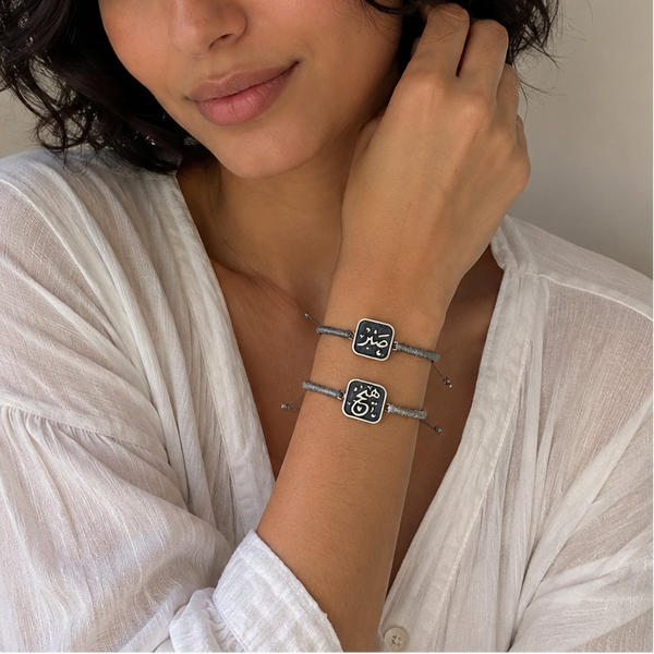 Woman wearing a white shirt and multiple bracelets on a neutral background
