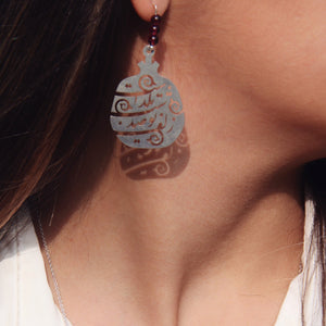 Close-up of a person wearing a silver earring with intricate design.