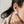 A close-up lifestyle shot of a model wearing a two-part earring. The earring features a textured silver disc on top with a small, round purple gemstone dangling below.