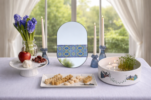Decorative mirror with a geometric pattern on a table with food and flowers. Persian new year Haftsin haftseen Nowruz norooz