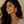 Woman with long dark hair wearing a beige top and gold Shir o khorshid Pahlavi coin earrings against a neutral background