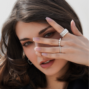 Woman wearing silver rings on a plain background