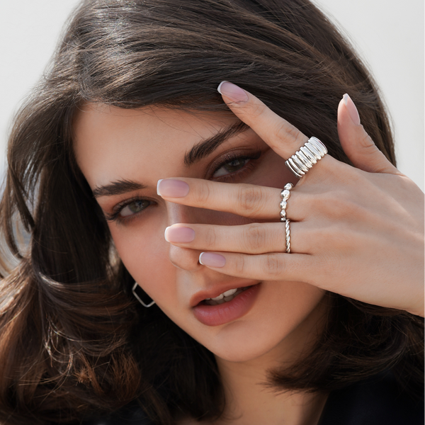 Woman wearing silver rings on a plain background
