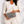 Woman in a white suit holding a gray clutch against a white background