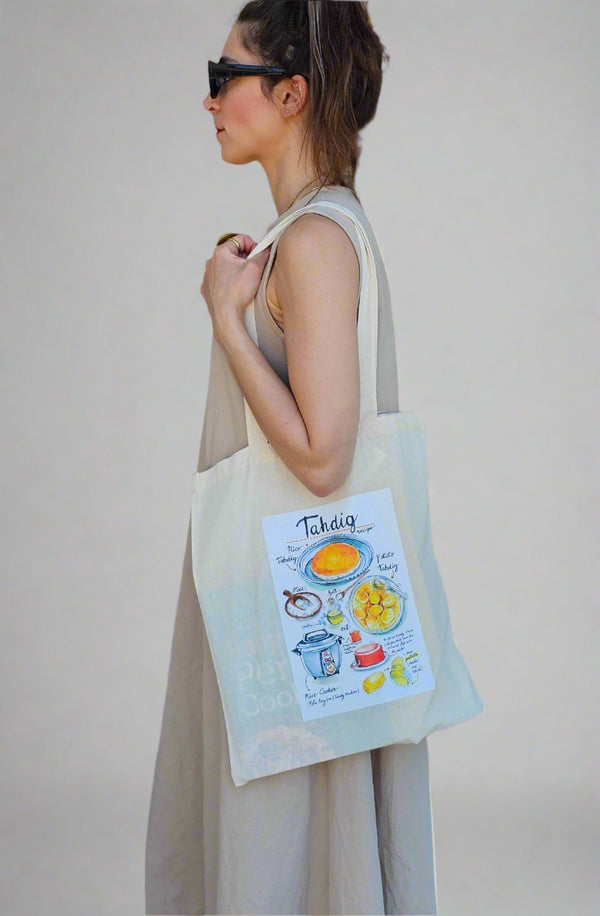 Woman holding a tote bag with a colorful design on a plain background