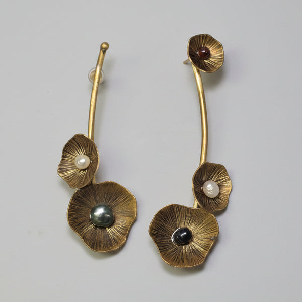 Set of three floral-shaped earrings with gemstones on a white background