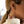 Close-up of a person's ear wearing multiple small hoop earrings, including a gold ear cuff and silver-toned hoop earrings, with a cream ribbed turtleneck sweater visible.
